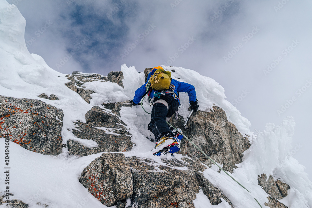一名登山运动员在冬季极端条件下攀登高山山脊。冒险攀登高山i峰