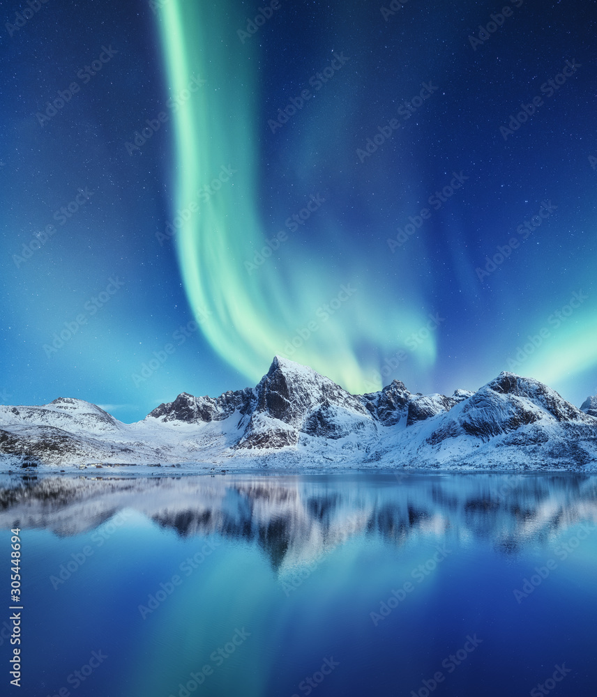 Mountains and northern lights in the sky. Reflections of the night sky and mountains on the water. W