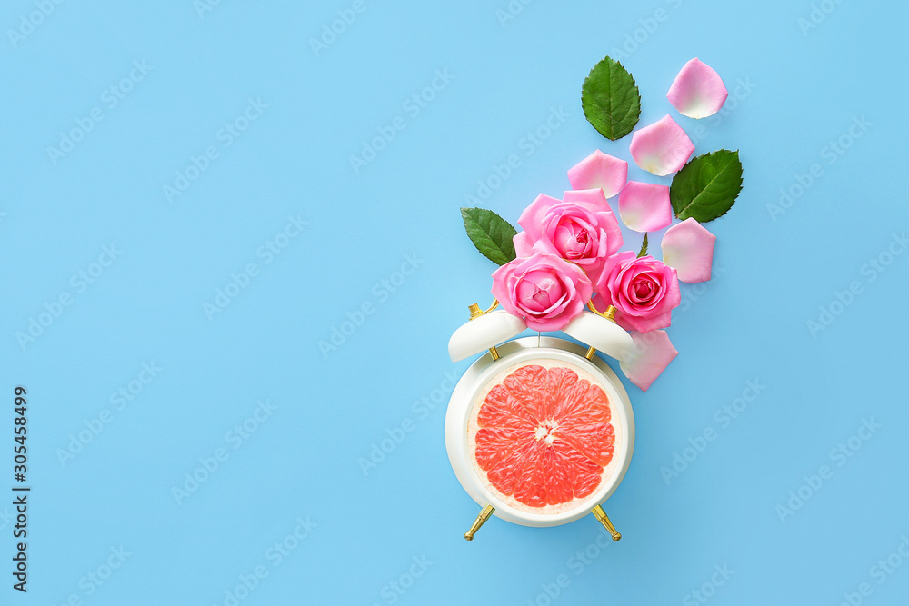 Beautiful rose flowers with alarm clock on color background
