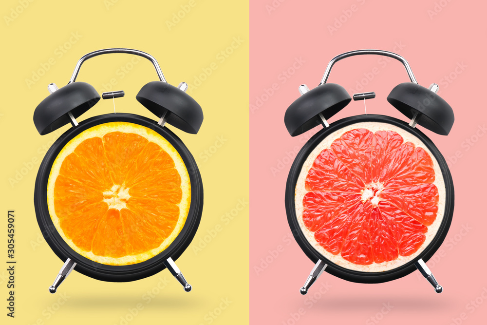 彩色背景下闹钟里的不同柑橘类水果