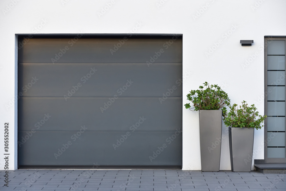 Modern gray garage, next to the Scandinavian-style house. Private garage with automatic door in a Eu