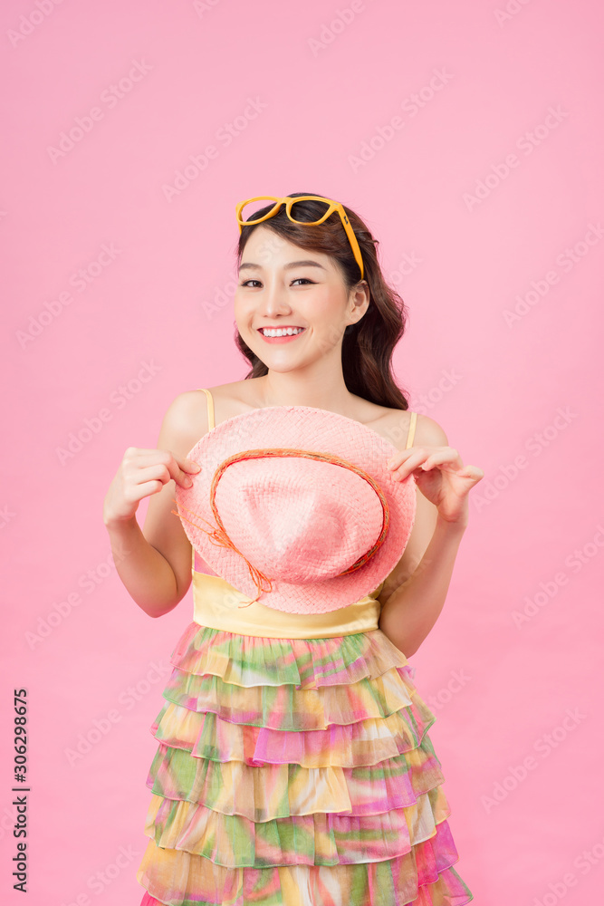 年轻快乐的亚洲女性，穿着时尚连衣裙，戴着墨镜，戴着夏帽微笑