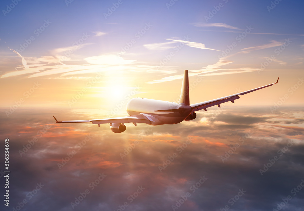 乘客乘坐的商用飞机在日落的阳光下飞越云层。快速旅行的概念，假期