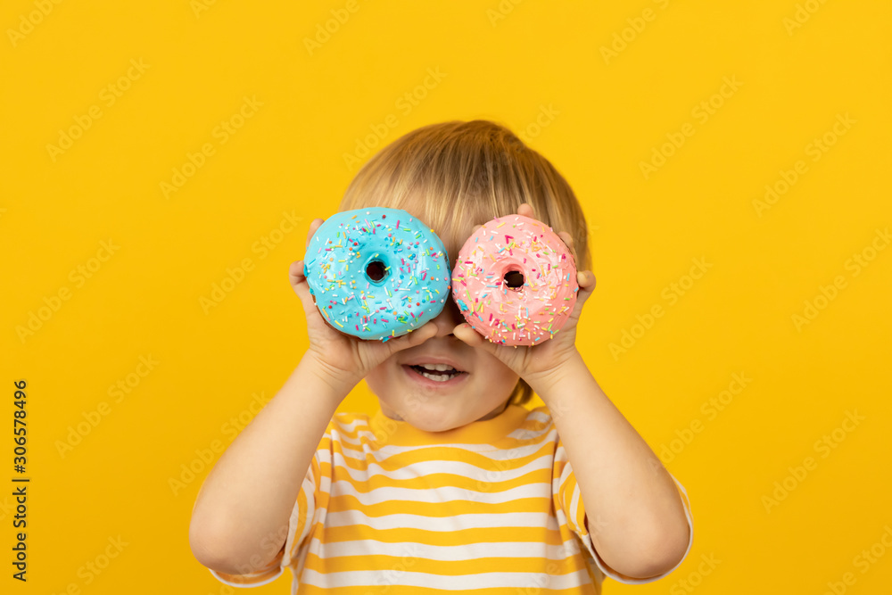 快乐的孩子拿着上釉的甜甜圈