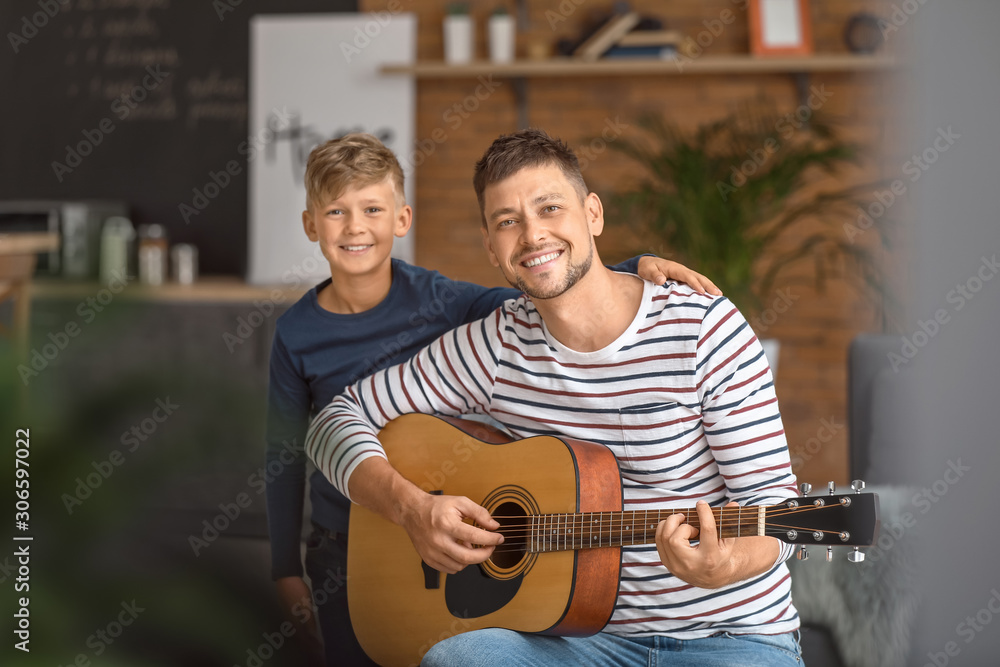 父亲和他的小儿子在家弹吉他