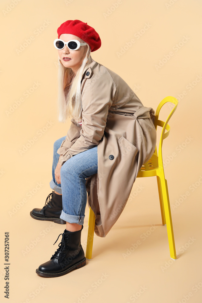 时尚成熟女性坐在彩色背景的椅子上