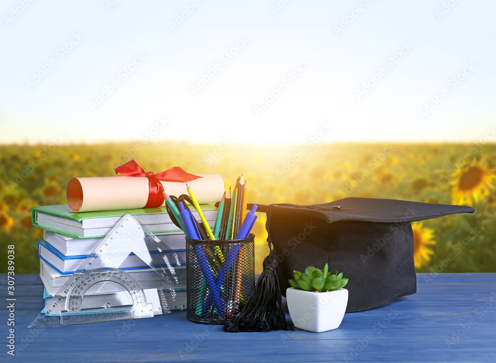 桌上的迫击炮板、文凭、文具和书籍。高中毕业的概念