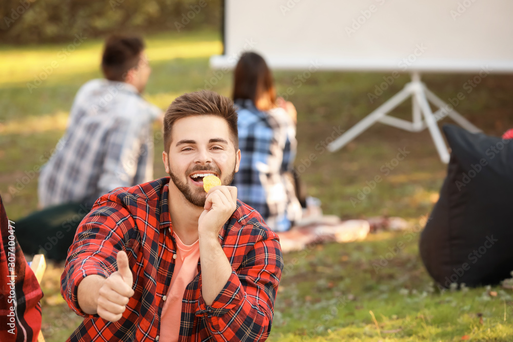 Young man eating chips in outdoor cinema