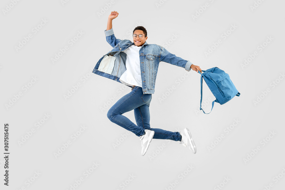 背着白底背包跳跃的非裔美国少年