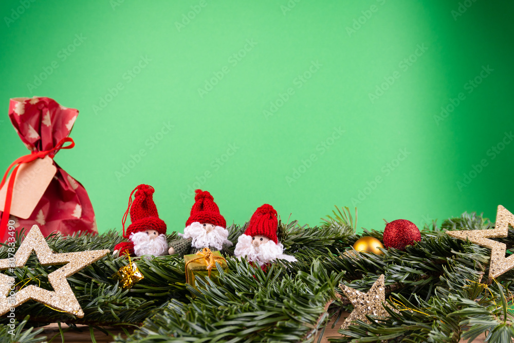 绿色背景前的圣诞装饰品（侏儒、礼物、星星、小玩意）和冷杉枝
