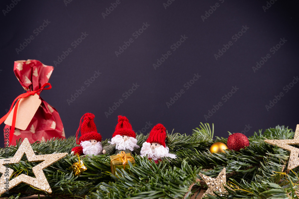 黑色背景前的圣诞装饰品（侏儒、礼物、星星、小玩意）和冷杉枝