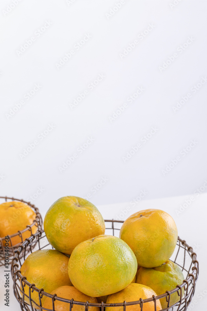 美丽的去皮橘子放在盘子和金属篮子里，在明亮的白色干净的桌子上隔离一个月