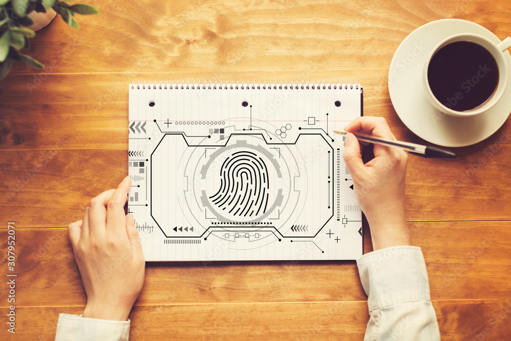 Fingerprint scanning theme with a person writing in a notebook on a wooden table