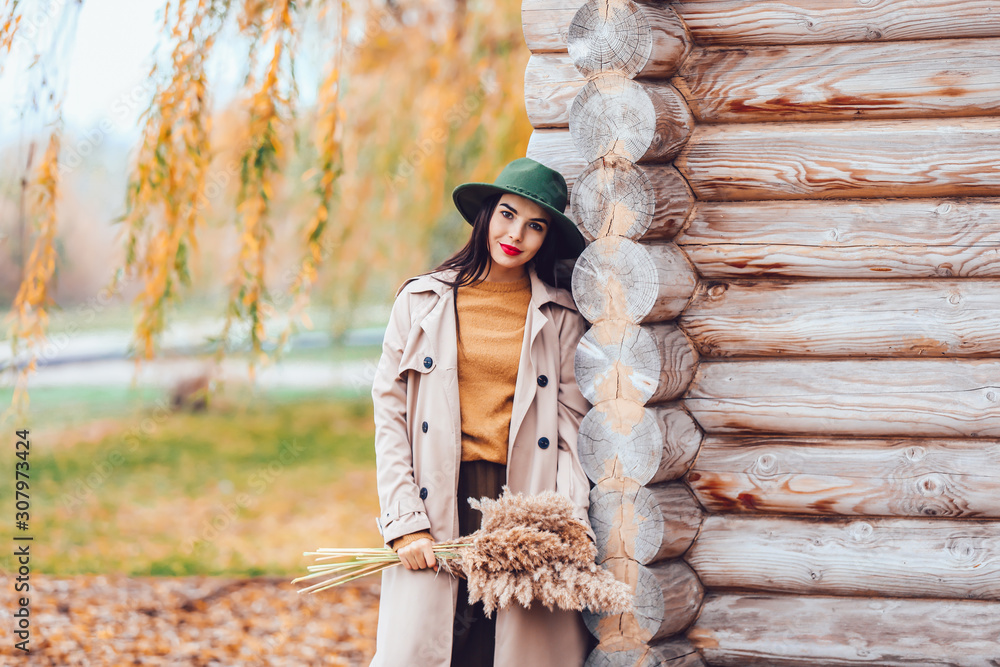 Beautiful young woman near wooden building outdoors on autumn day