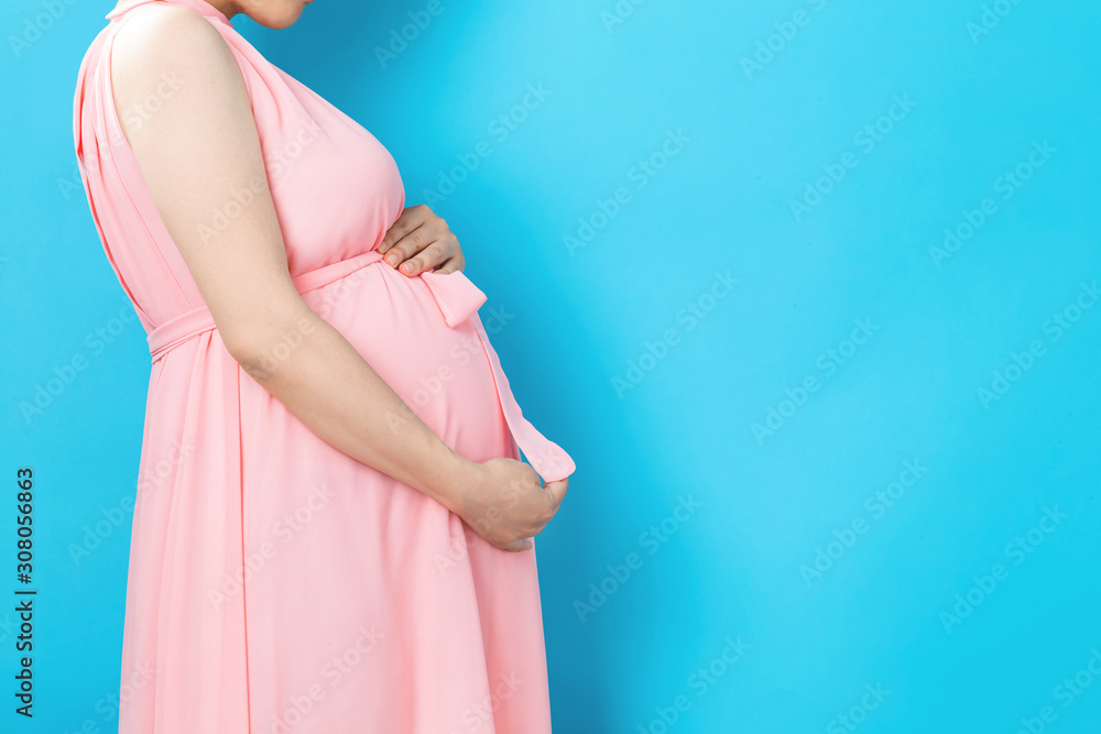孕妇在坚实的背景下撑着肚子