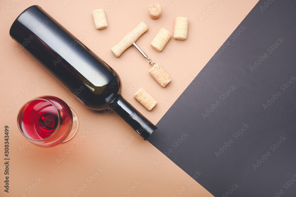 Bottle and glass of wine with corks and opener on color background