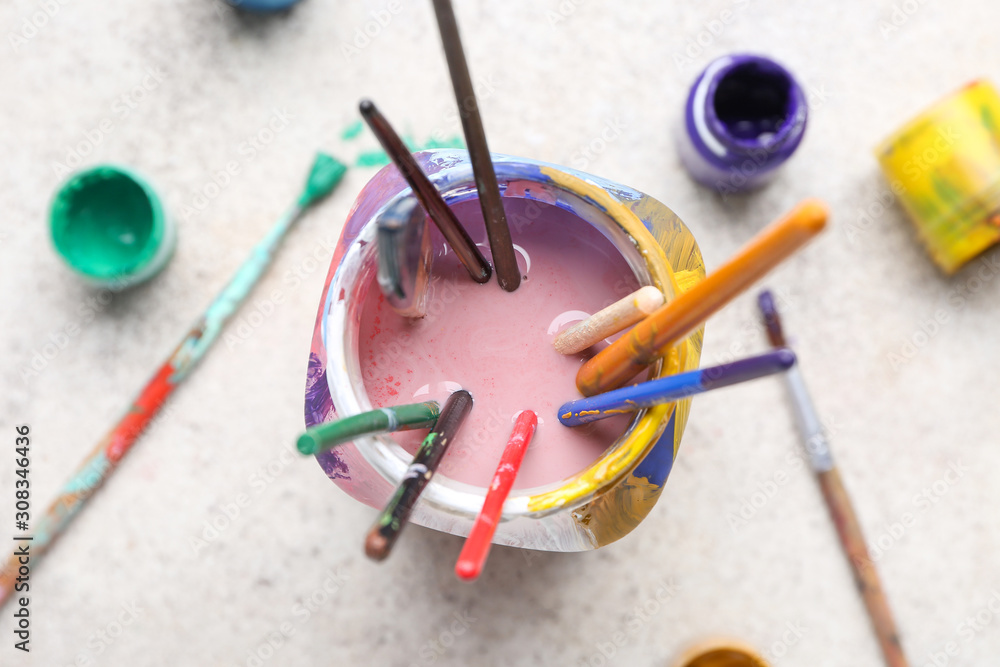浅色背景上有一套艺术家画笔和颜料的罐子
