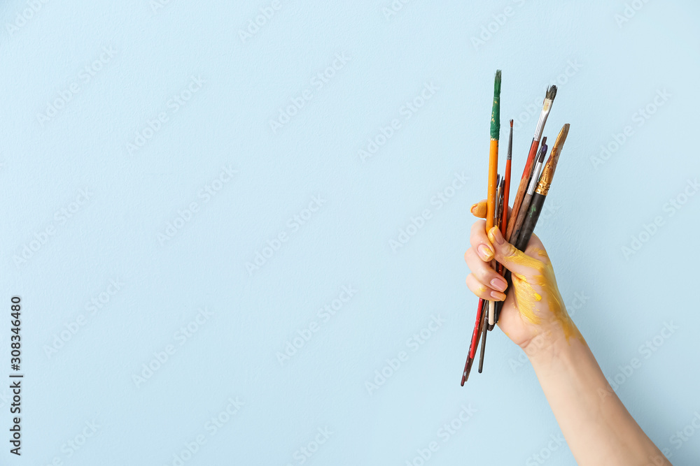 艺术家在彩色背景上用画笔创作的手