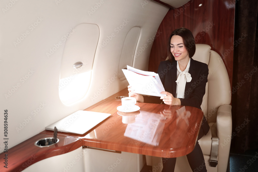 Businesswoman reading newspaper on board the modern private airplane