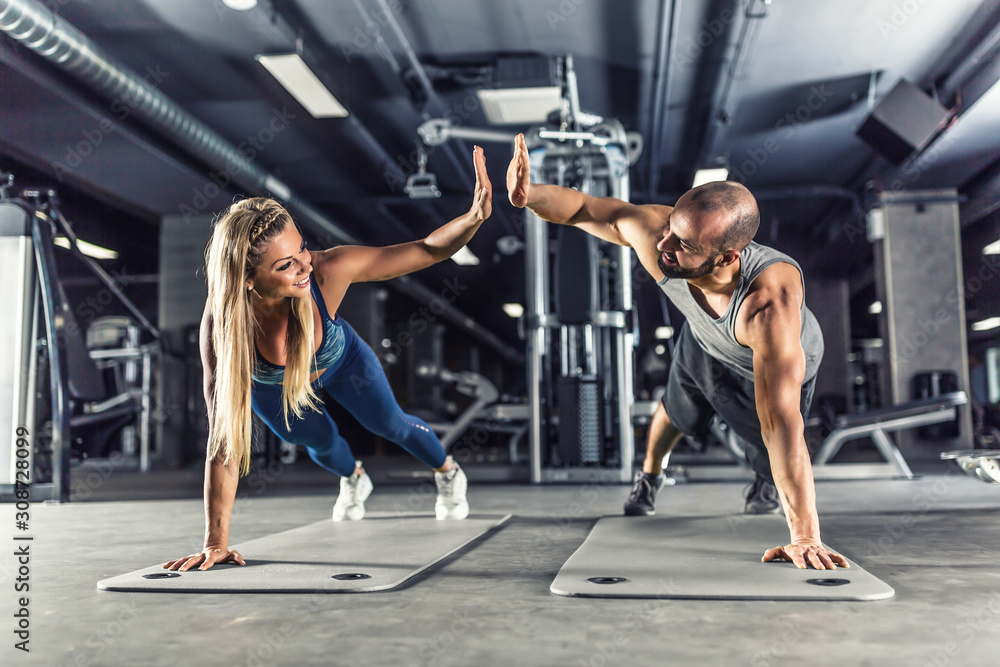 运动情侣在健身中心进行平板运动锻炼。男女在健身中心练习平板运动
