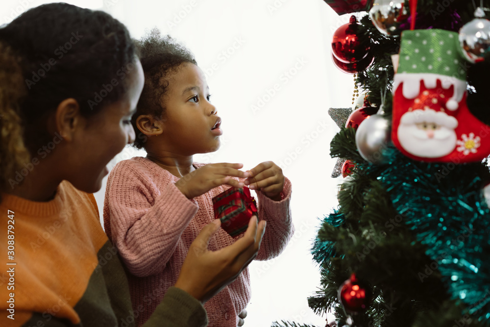 母女非裔美国女孩用装饰圣诞树，布置圣诞礼