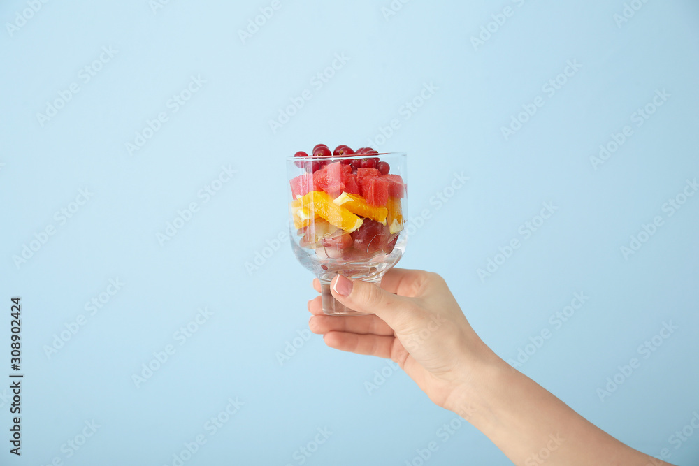女性手配美味的彩色背景玻璃水果沙拉