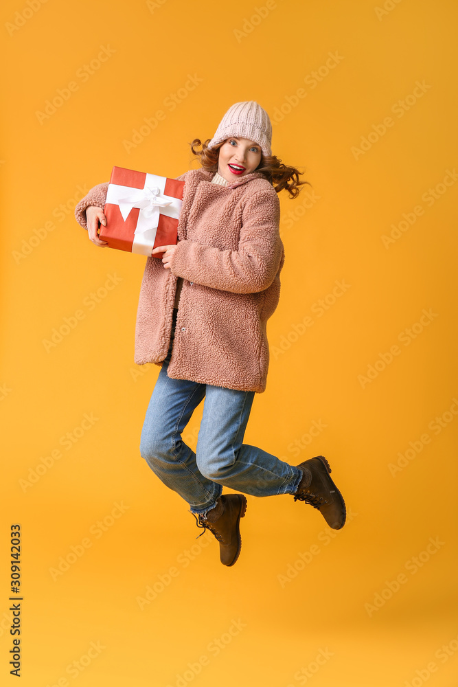穿着冬装，背景是圣诞礼物的跳跃年轻女子