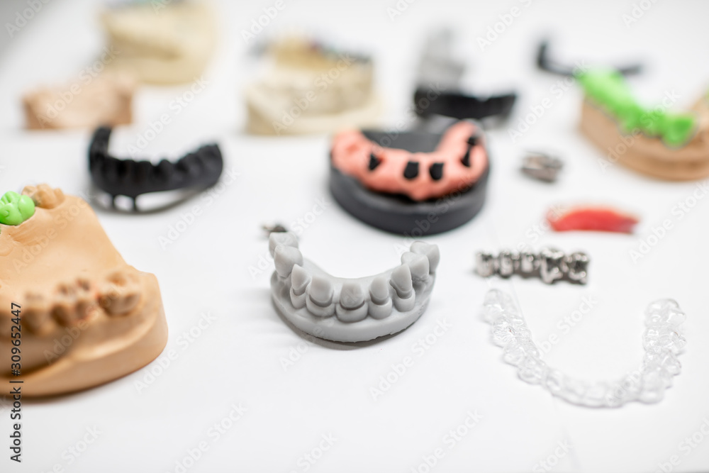 白色背景上有种植牙和牙冠的各种人工下颌模型。概念