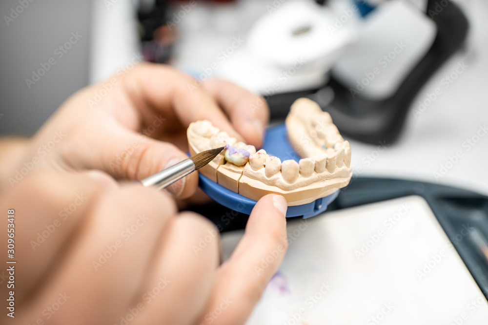 牙科技师在实验室用画笔为假牙上色，特写。Co