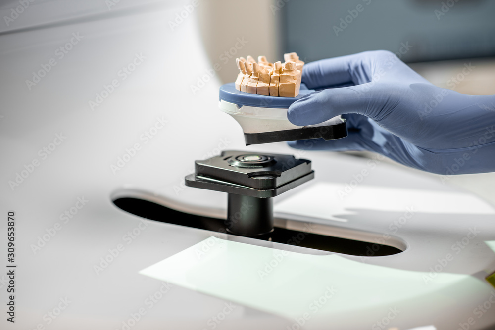Dental technician placing jaw model into the 3d scanner at the laboratory, close-up