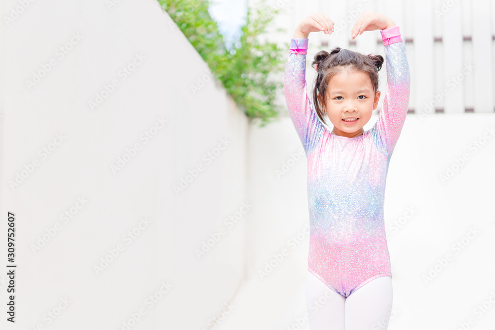 Little ballerinas in ballet studio.Cute little asian girl in a leotard and skirt lifting her leg dur