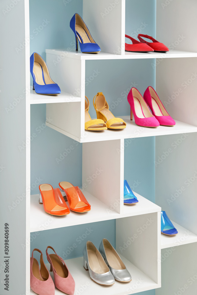 Shelf unit with stylish shoes near color wall