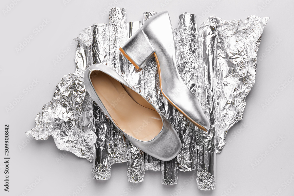 Stylish female shoes and foil on grey background