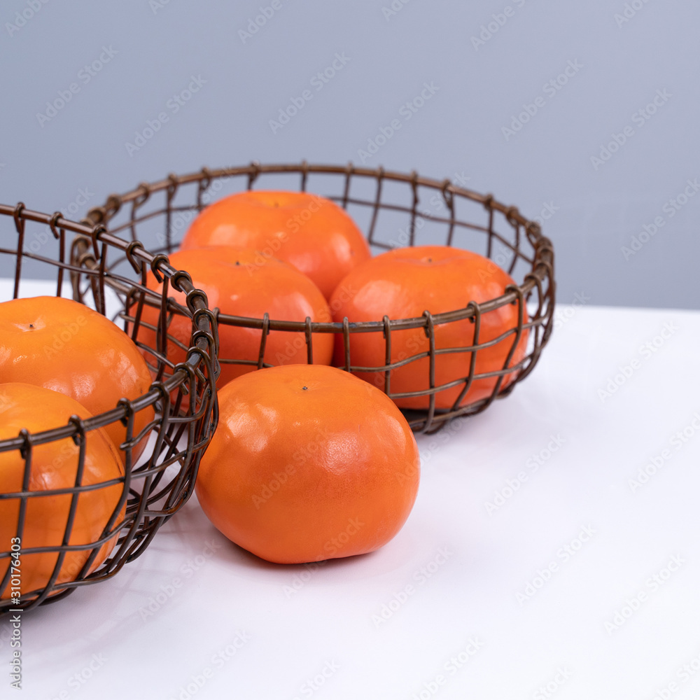 新鲜漂亮的甜柿子切片，隔离在白色厨房桌子上，背景是灰蓝色