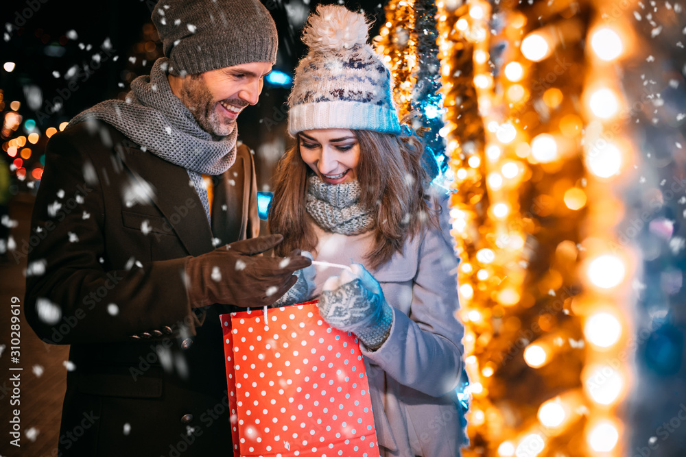 Couple with a Christmas gift after shopping walks on a decorated street