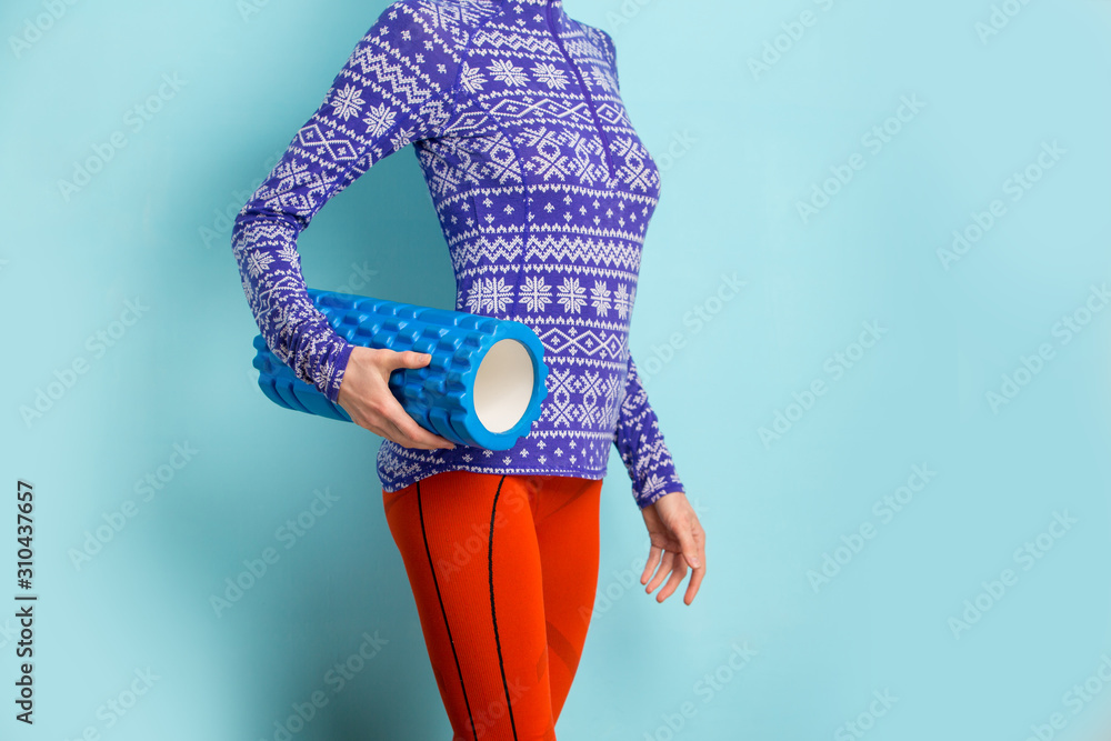 准备进行筋膜训练的年轻女子，手里拿着印有雪纹的蓝色背景筋膜卷