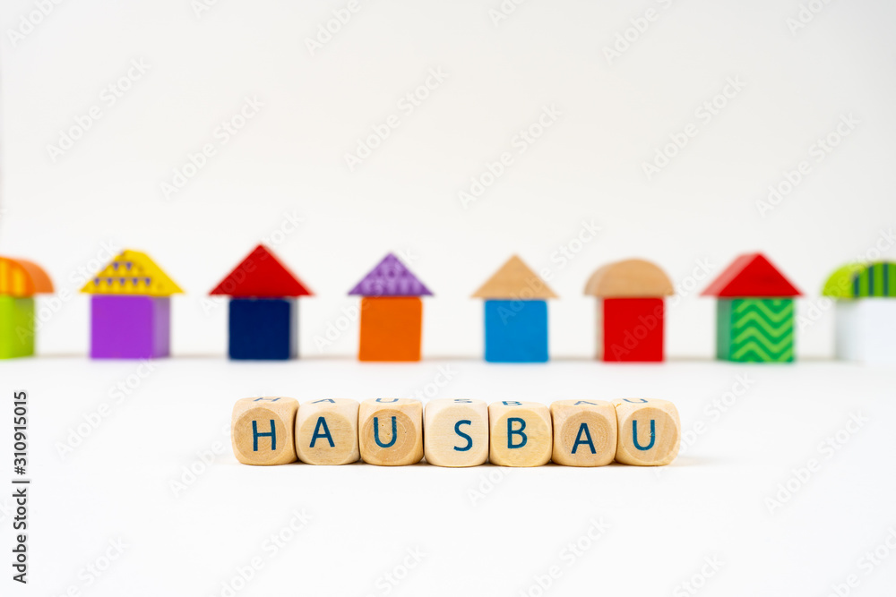 写着Hausbau（德语中建造房屋的意思）的木块在五颜六色的玩具hou前面