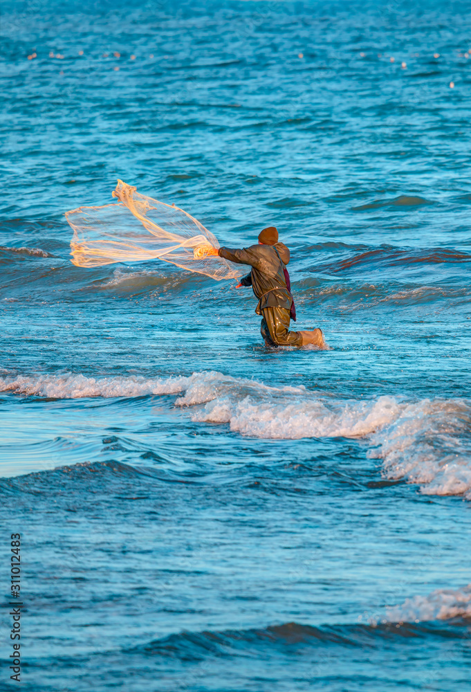渔民因扔渔网而站在海里撒网捕捞咸水鱼