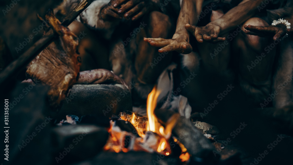 部落史前猎人聚集者试图在篝火旁取暖，手牵手的特写