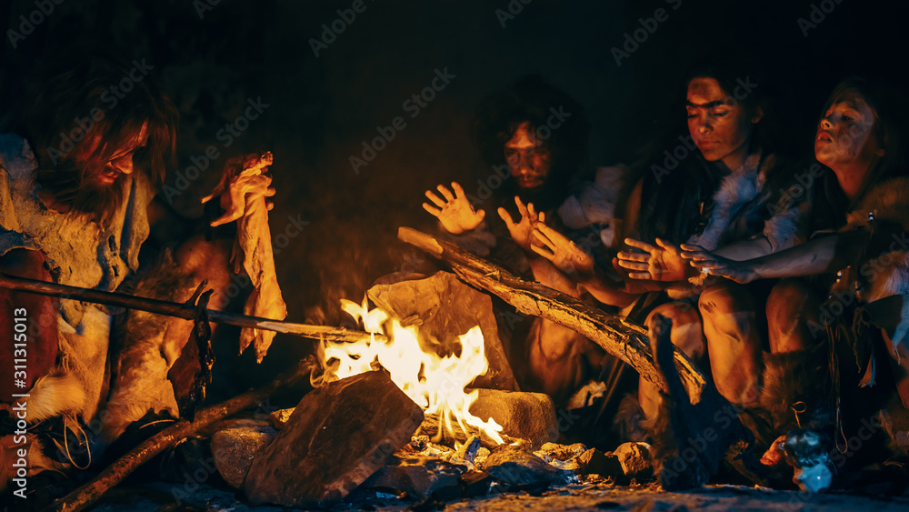 尼安德特人或智人家庭在篝火上烹饪动物肉，然后食用。史前部落