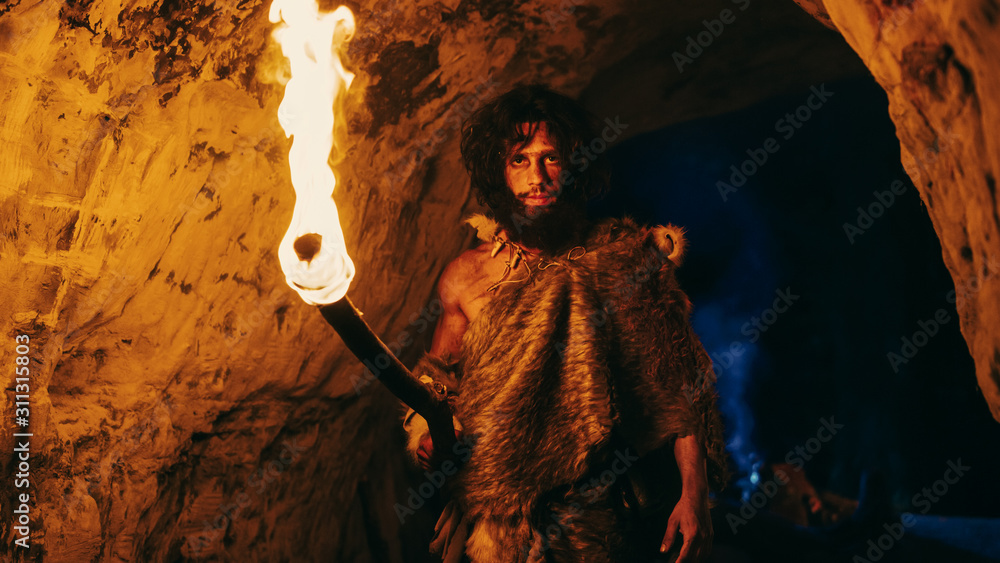 《原始洞穴人身穿兽皮夜探洞穴，手持火炬Lo的画像》