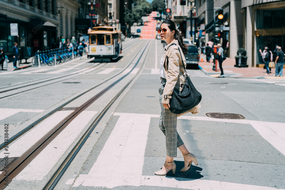 年轻时尚的亚洲华裔女性穿越旧金山斑马线的全长侧视图