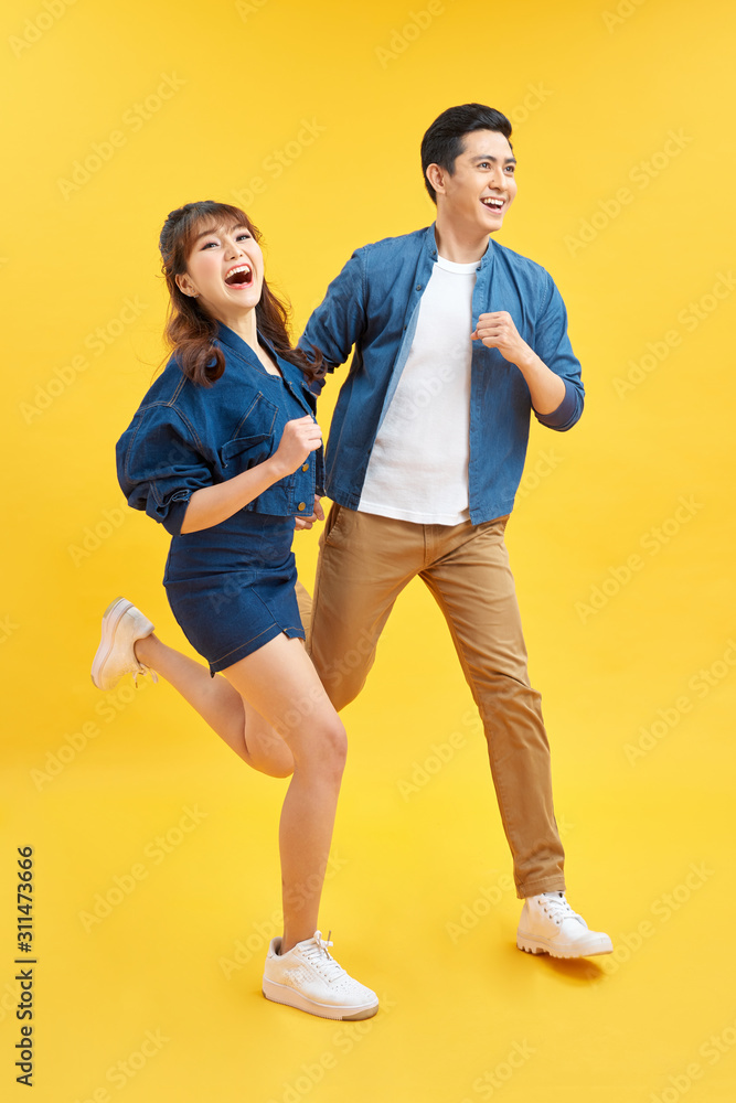 迷人的微笑的亚洲年轻夫妇在黄色的工作室背景下感到幸福和惊讶