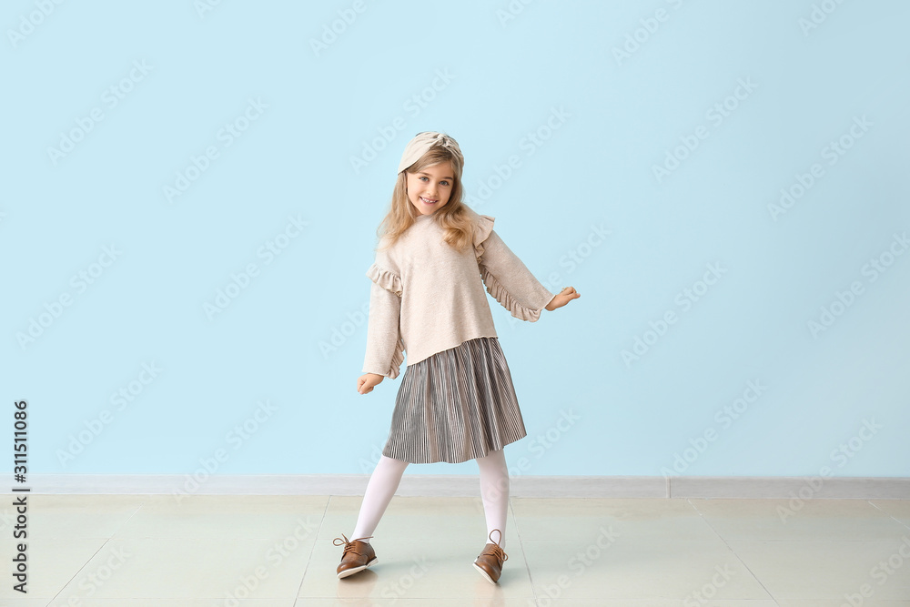 穿着秋装的可爱小女孩靠近彩色墙