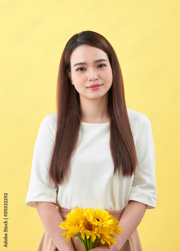 幸福的年轻女子手中拿着一束黄色背景的鲜花