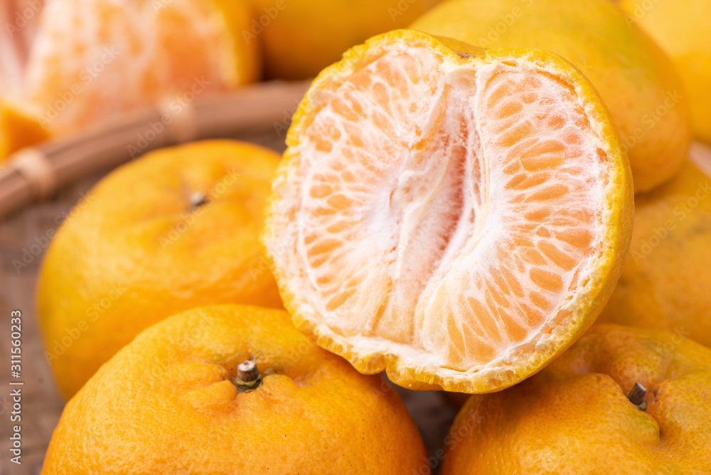 新鲜、美丽的橙色橘子放在深色木桌上的竹筛上。时令、传统