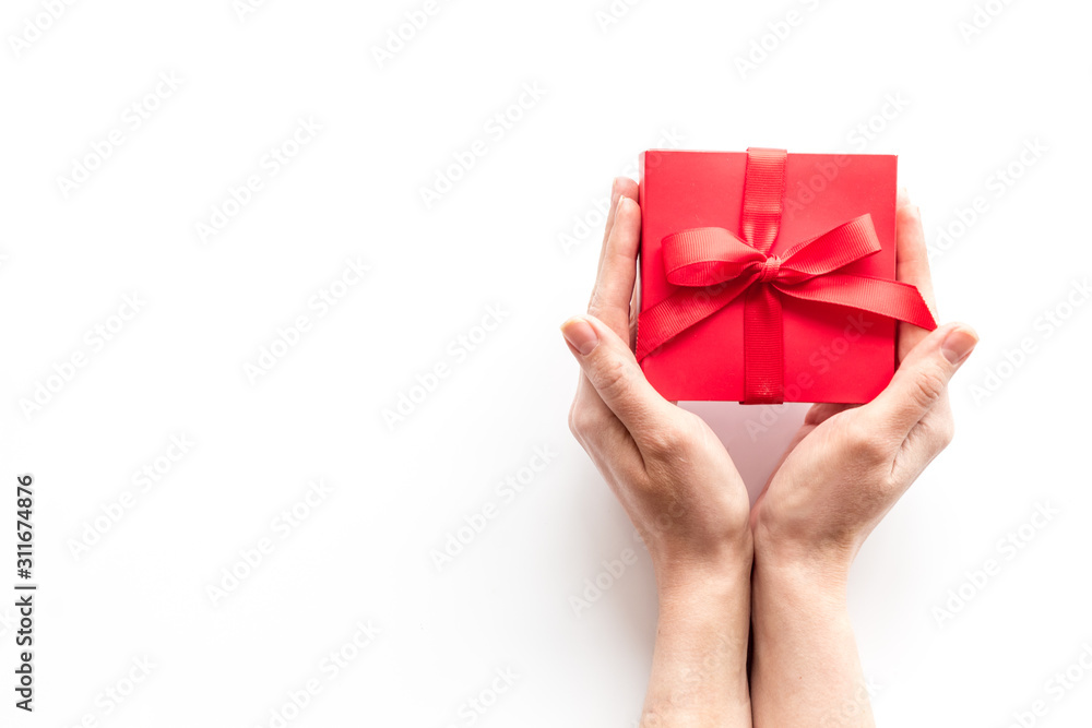在情人节送一份礼物。女性手拿白色背景的漂亮红色礼盒。