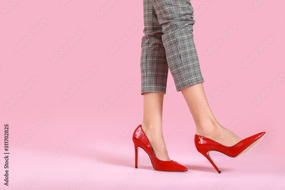 彩色背景下穿高跟鞋的年轻女性的腿