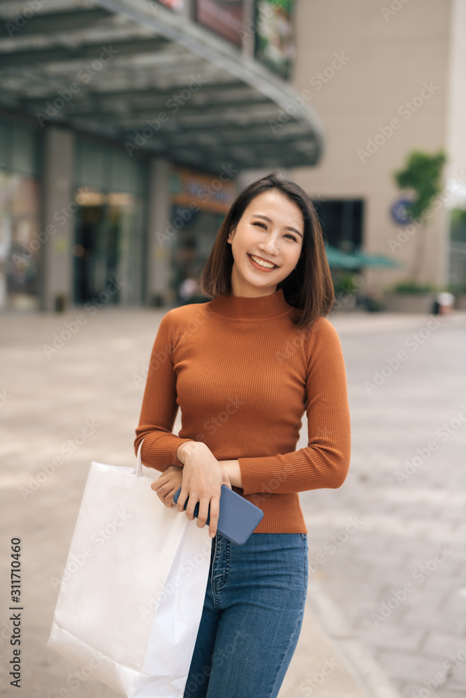 幸福、消费主义、销售和人的概念——面带微笑的年轻亚洲女性在你身边拿着购物袋