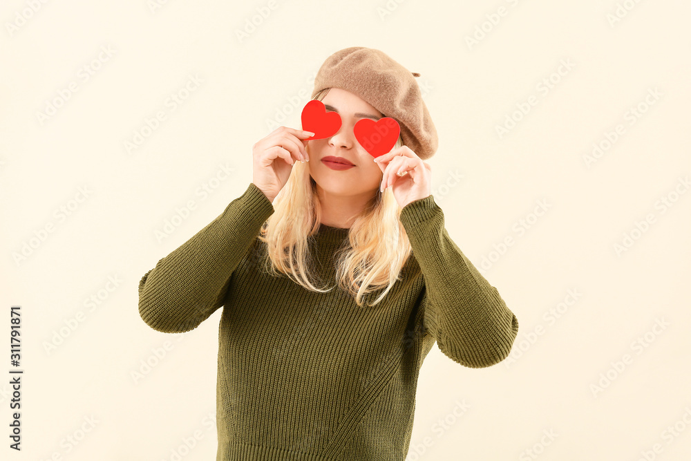 Beautiful young woman with small red hearts on color background